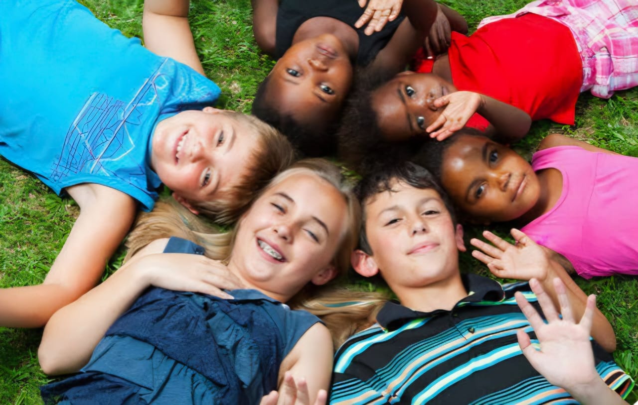 Children Smiling in Circle on Grass